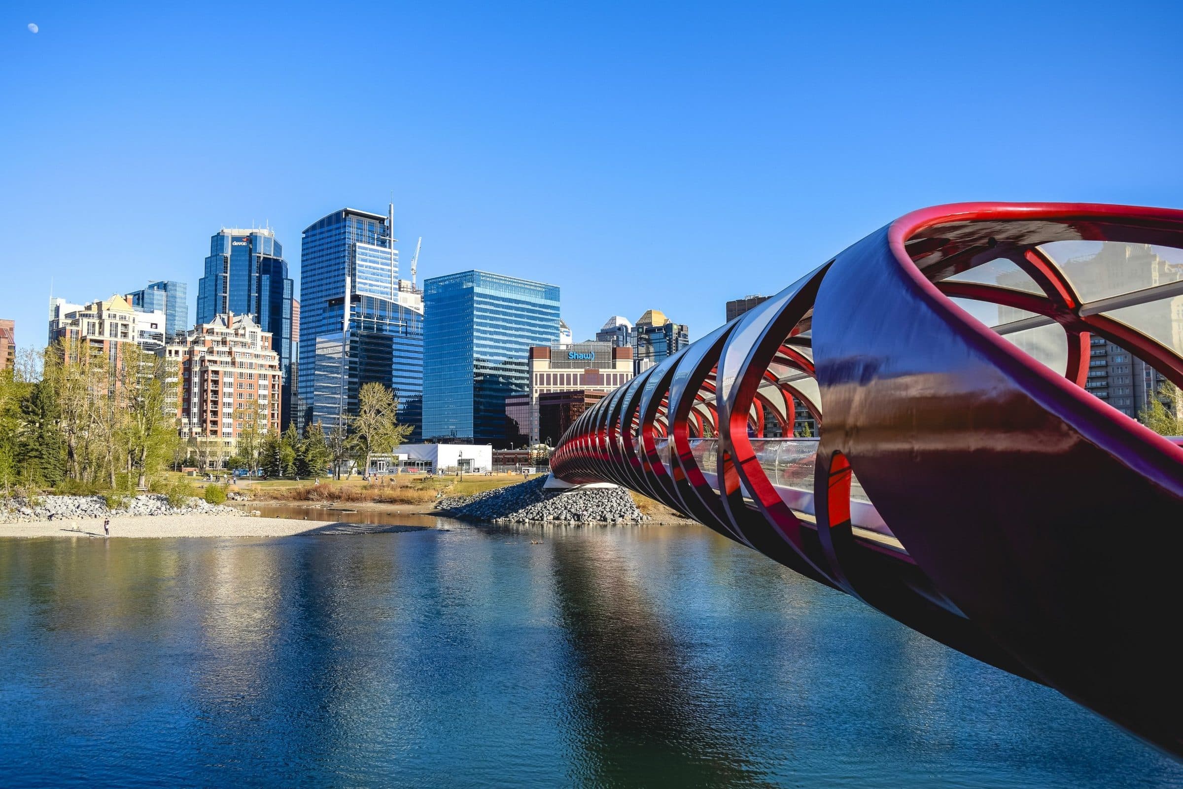 The red Peace Bridge crossing the Bow River, with downtown Calgary's towers behind it under a clear blue sky